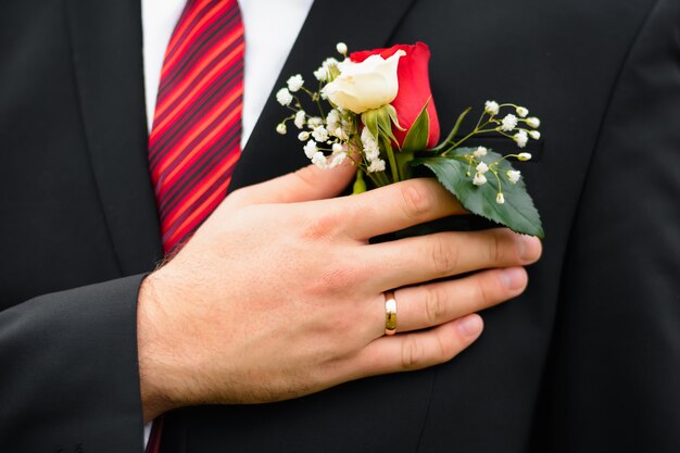 Foto boutonniere van verse roze bloem op het bruidegomkostuum