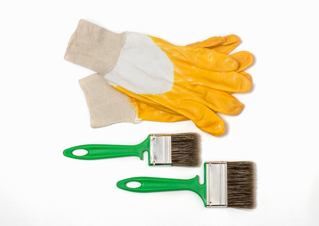 Bouw beschermende handschoenen in geel met twee groene borstels op een witte achtergrond.