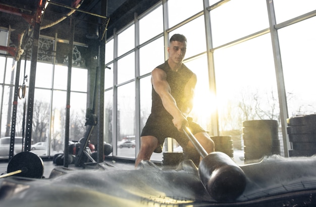 Bouw jezelf Jonge gespierde blanke atleet die traint in de sportschool en krachtoefeningen doet