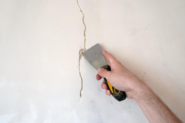 Bouw man werknemer repareren van een scheur muur van een huis pleisterwerk cement op muur