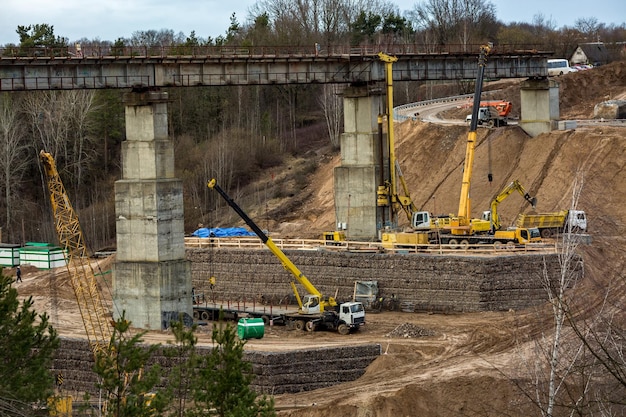 Bouw of reconstructie van een snelweg betonnen brug over een brede rivier bouwmachines vrachtwagens en kranen werken