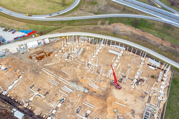 Bouw van een groot logistiek magazijn bovenaanzicht van de bouwplaats met betonblokken bij de rode kraan