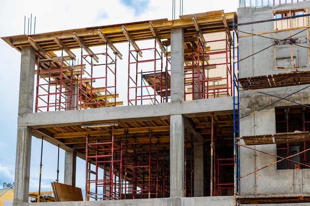 Bouw van een nieuw monolithisch huis van gewapend beton Steigers op de gevel van een gebouw in aanbouw Werken op hoogte op een bouwplaats