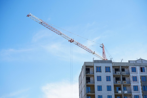 Bouw van een woongebouw en een hoogbouwkraan tegen de blauwe lucht Bouwplaats