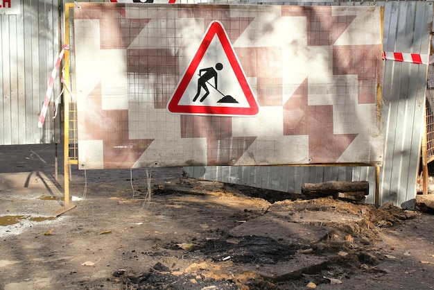 Bouw weg driehoek teken op metalen hek achtergrond. Voorbereiding voor het leggen van nieuwe asfaltpaveme