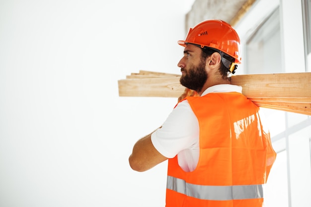 Bouwer man in veiligheidshelm met hout op bouwplaats close-up