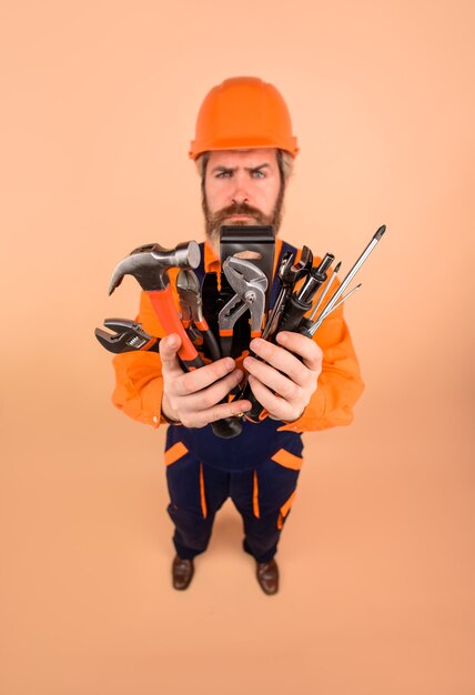 Bouwer man serieuze werker houdt reparatie tools gebouw bouwer in bouw helm reparatie