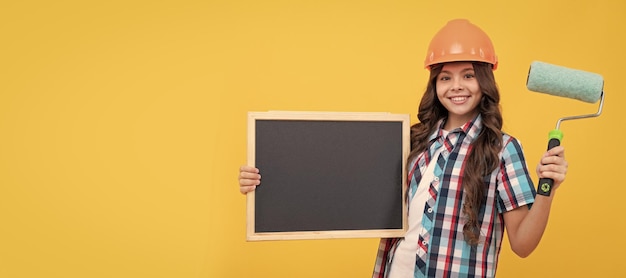 Bouwer tiener meisje in helm gelukkig kind met krullend haar in helm houden verfroller en school