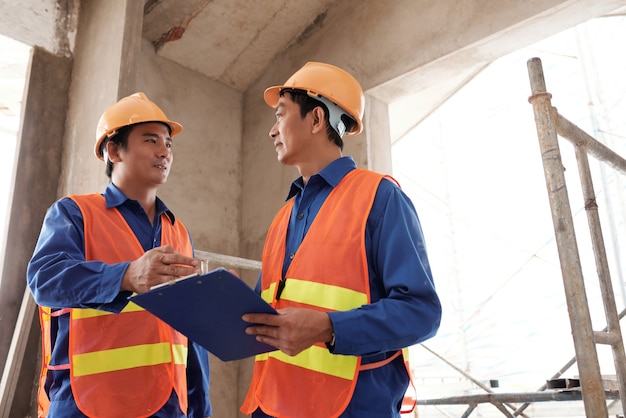 Bouwers in uniform bespreken werkplan voor de dag wanneer ze elkaar ontmoeten op de bouwplaats