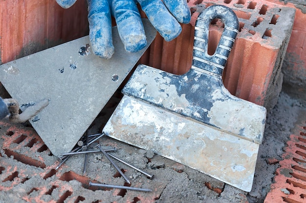 Bouwgereedschap voor het leggen van stenen en blokken metselaarsgereedschap hamer spatel troffelhandschoenen handgereedschap op de achtergrond van metselwerk