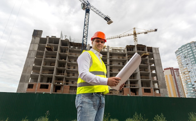 Bouwingenieur in veiligheidshelm op bouwplaats bij bewolkte dag