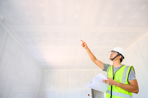 Bouwingenieur of architect met ontwerpdocumenten Bekijk het interieur en inspecteer de muren en plafonds van het huis tijdens het ontwerp van de bouwplaats van het huis.