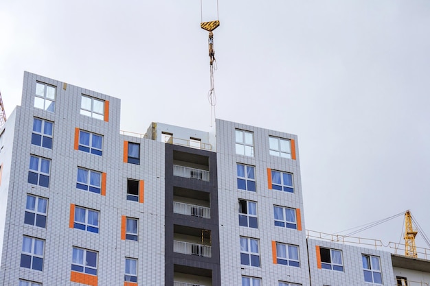 Bouwkraan en huis in aanbouw tegen de achtergrond van een regenachtige lucht