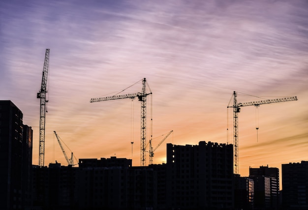 Bouwkraan met de gebouwen tegen een zonsondergang.