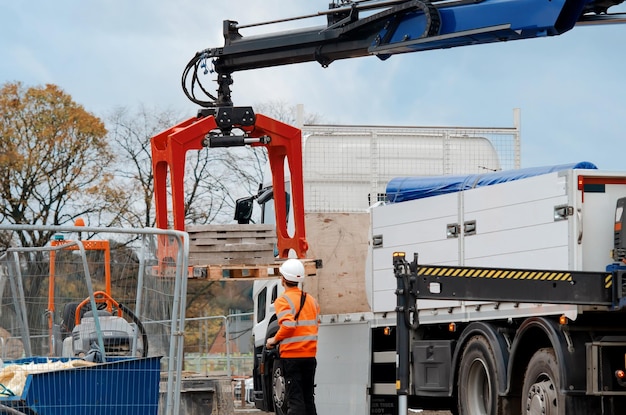 Foto bouwmaterialen geleverd op locatie en gelost door hydraulische autolaadkraan