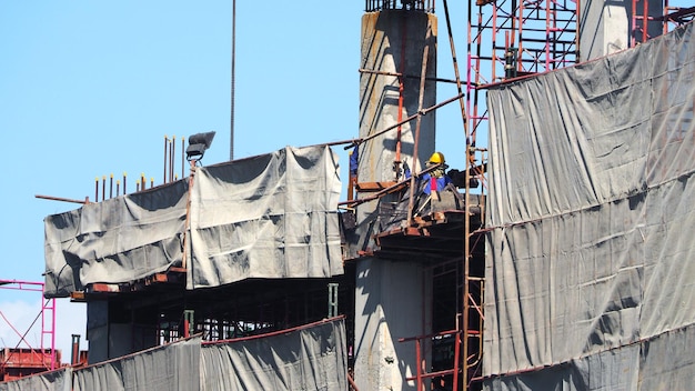 Bouwplaats en arbeider die werkt aan hoogbouw en betonstaalmateriaal.