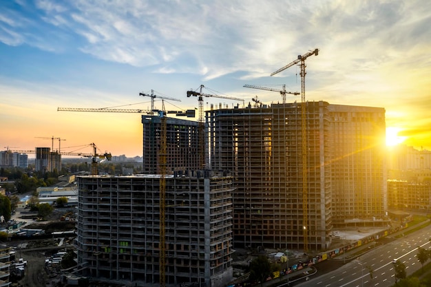 Bouwplaats met kranen bij zonsondergang Bouw van een flatgebouw