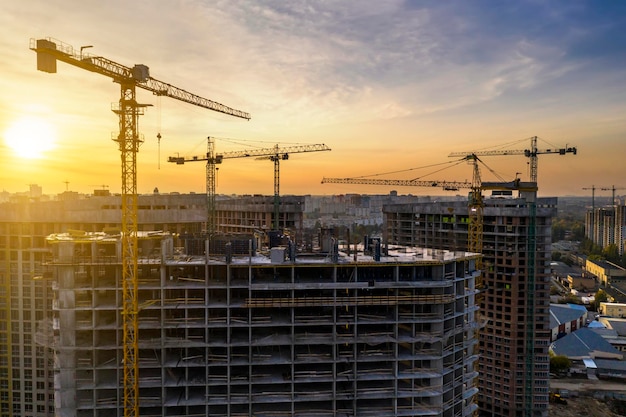 Bouwplaats met kranen bij zonsondergang Bouw van een flatgebouw