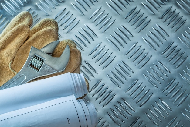 Bouwplannen verstelbare moersleutel beschermende handschoenen op gegolfde metalen achtergrond