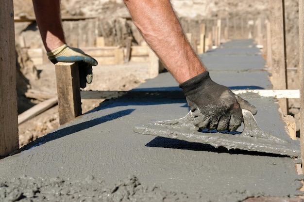 Bouwvakker die een betonnen mengsel voor de fundering van een huis verspreidt