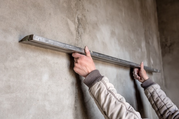 Foto bouwvakker stukadoors een muur met leveler