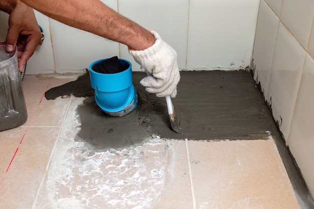 Bouwvakkers borstelen waterdicht cement op tegelvloeren in de badkamer.