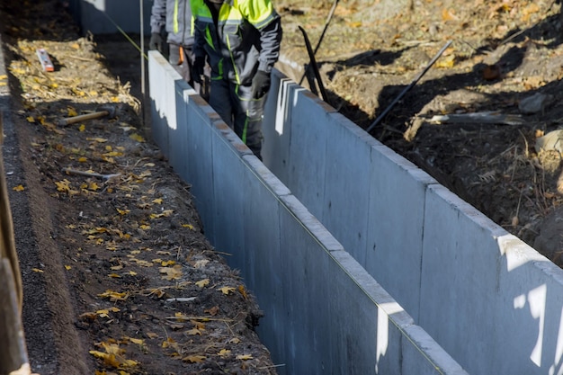 Bouwvakkers die geprefabriceerde u-vormige betonnen afvoer installeren bij de wederopbouwweg
