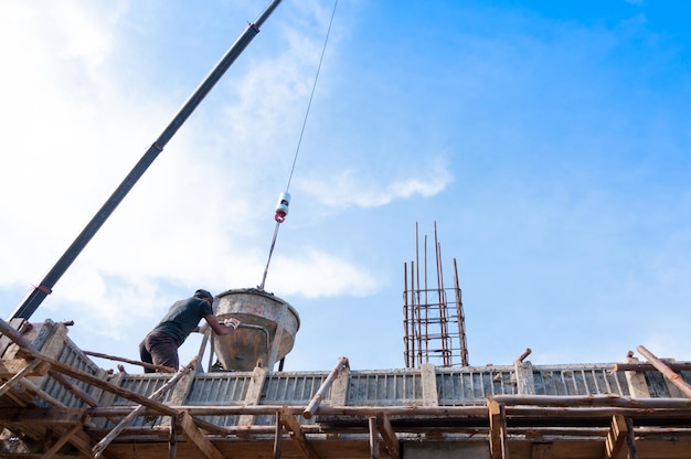 Bouwvakkers op de bouwplaats die beton in vorm gieten Man werkt op hoogte met blauwe lucht op de bouwplaats