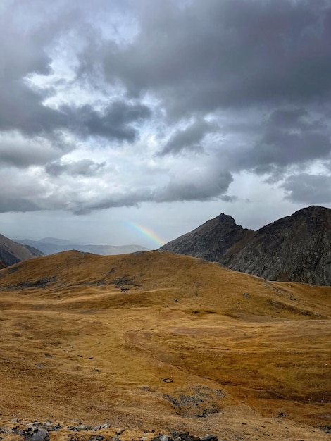 Boven een bergketen is een regenboog te zien in de lucht.