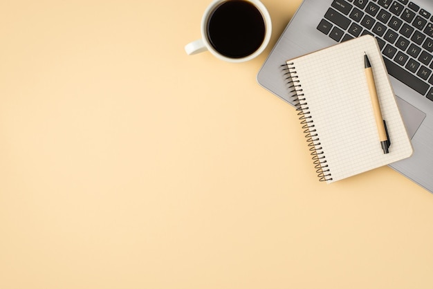 Boven foto van grijze laptop notitieblok met pen en kopje koffie geïsoleerd op de beige achtergrond met lege ruimte