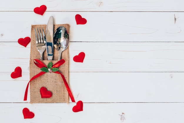 Boven houten tafel set zilverwerk en rood hart voor Valentijnsdag met ruimte.