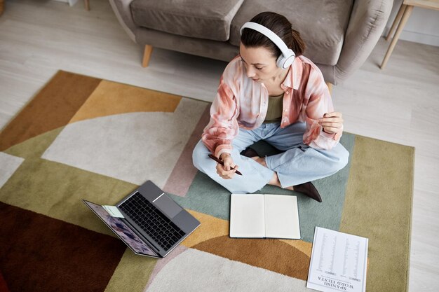 Foto boven schot van jonge vrouw die naar het scherm van de laptop kijkt en naar de tutor luistert