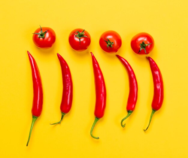 Boven uitzicht op Chili peper en tomaten op gele achtergrond