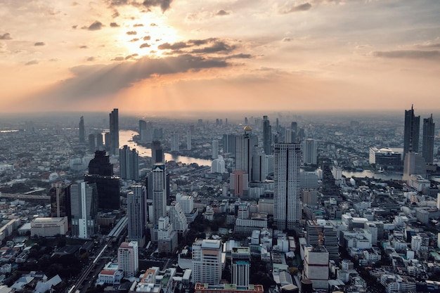 Boven uitzicht op de zonsondergang op een druk gebouw met de Chao Phraya-rivier in de stad Bangkok, Thailand