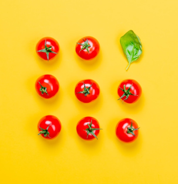 Boven uitzicht op tomaten en basilicum op gele achtergrond