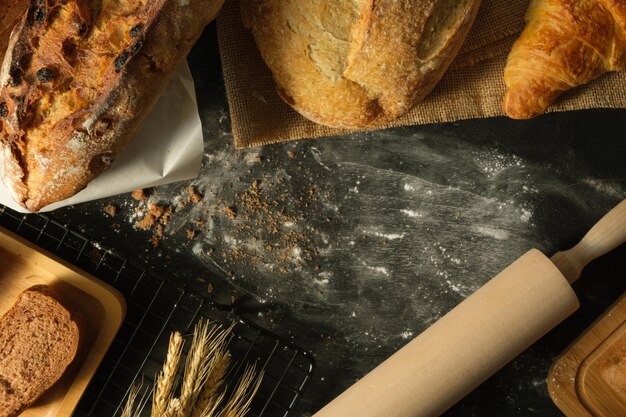 Boven weergave van assortiment zelfgemaakte broodtarwe en houten deegroller op rustieke tafel