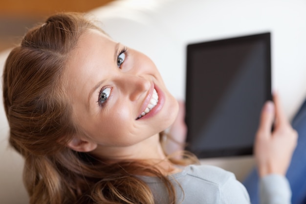 Boven weergave van lachende vrouw met tablet op de bank