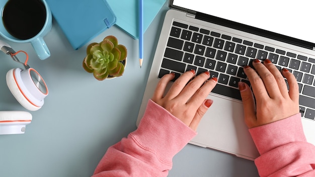 Boven weergave van vrouw handen typen op laptopcomputer op haar bureau.