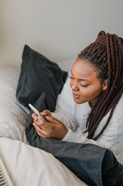 Bovenaanzicht Afro-Amerikaanse vrouwelijke student gekleed terloops met mobiele telefoon en het typen van berichten