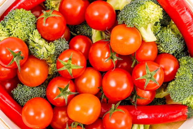 Bovenaanzicht beeld van bulk cherrytomaatjes, rauwe stukjes broccoli en hete rode chilipepers