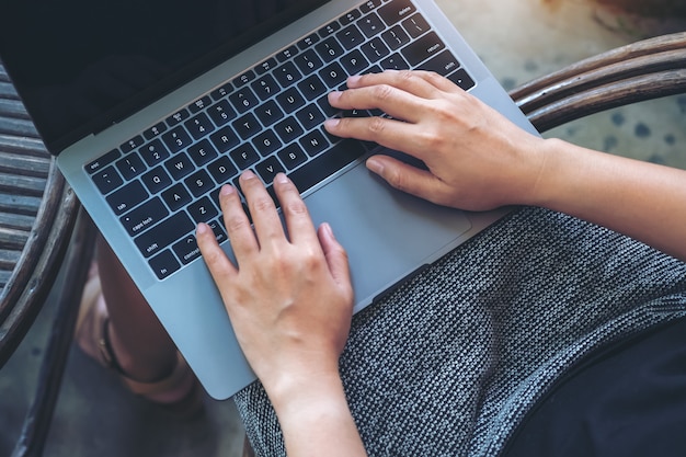 Bovenaanzicht beeld van vrouw met behulp van en typen op laptop toetsenbord zittend in de buitenlucht