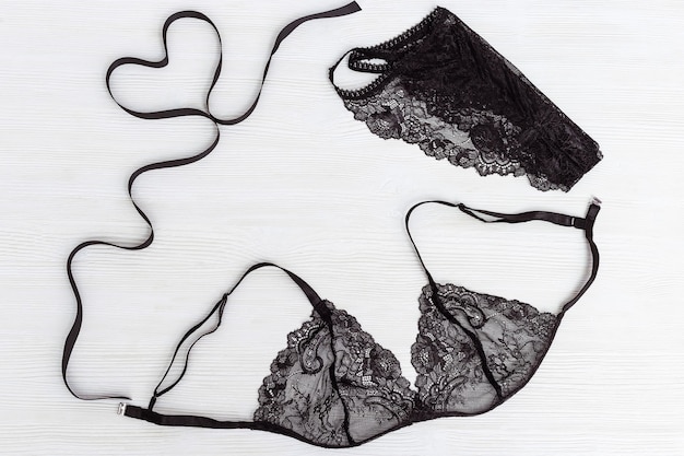 Bovenaanzicht black lace lingerie ingesteld op wit hout. figuur van hart van zwart lint