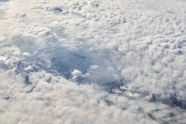 Bovenaanzicht boven wolken vanuit vliegtuigraam, dikke witte blauwe wolken zien eruit als zacht schuim