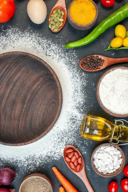 Bovenaanzicht bruin houten bord met groenten, eieren en kruiden op donkere achtergrond suiker kleur cake witte thee koekje salade eten