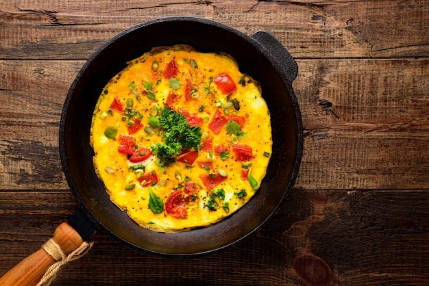 Bovenaanzicht close-up omelet met oude gietijzeren pan op houten achtergrond met kopie ruimte