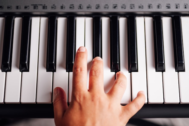 Bovenaanzicht close-up van een vrouwelijke hand die de sleutels van een elektronische synthesizer speelt