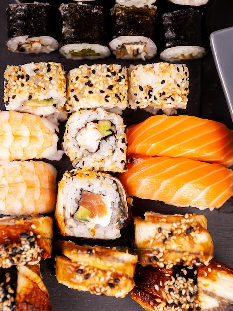 Bovenaanzicht close-up van sushi rollen in verscheidenheid op zwarte stenen achtergrond