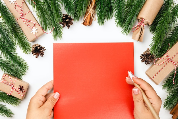 Bovenaanzicht close-up vrouwelijke handen met rood karton met kopie ruimtekaart voor nieuwjaarsgroeten in f...