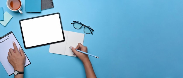 Bovenaanzicht creatieve vrouw die werkt met digitale tablet en aantekeningen maakt op notebook.