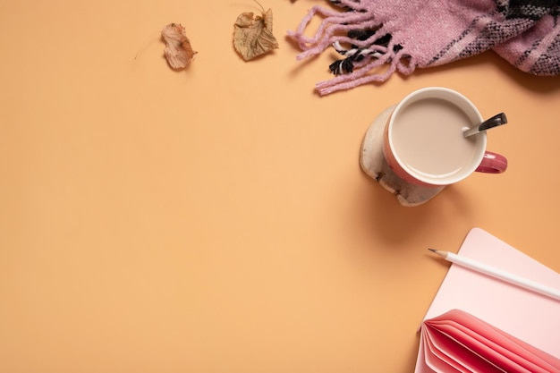 Bovenaanzicht desktop met koffiekopje notitieboekje en plaid op gekleurde achtergrond Herfst of winter werktafel plat leggen